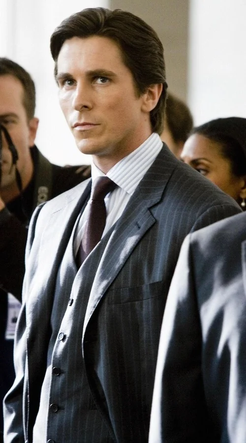 Christian Bale como Bruce Wayne con un traje gris de Armani